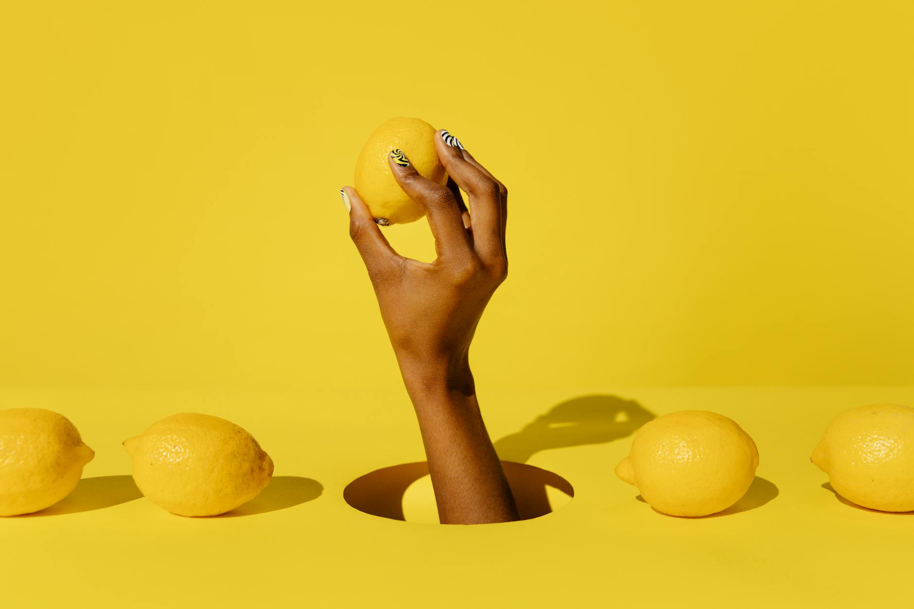 A hand holding a lemon against a vivid yellow background, symbolizing refreshed sensitivity and renewed pleasure.