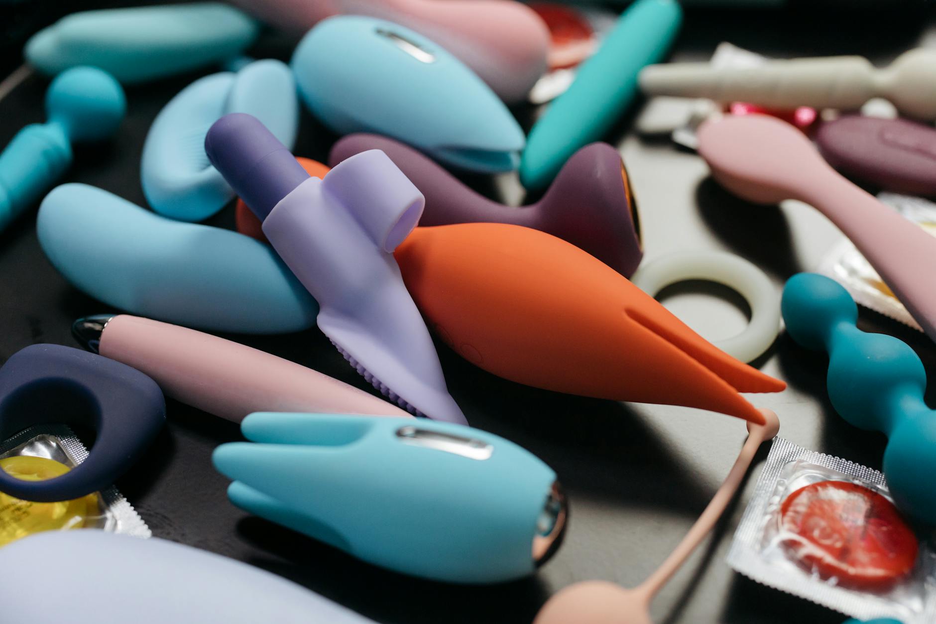 Person holding blue and pink silicone vibrators in contemplative moment