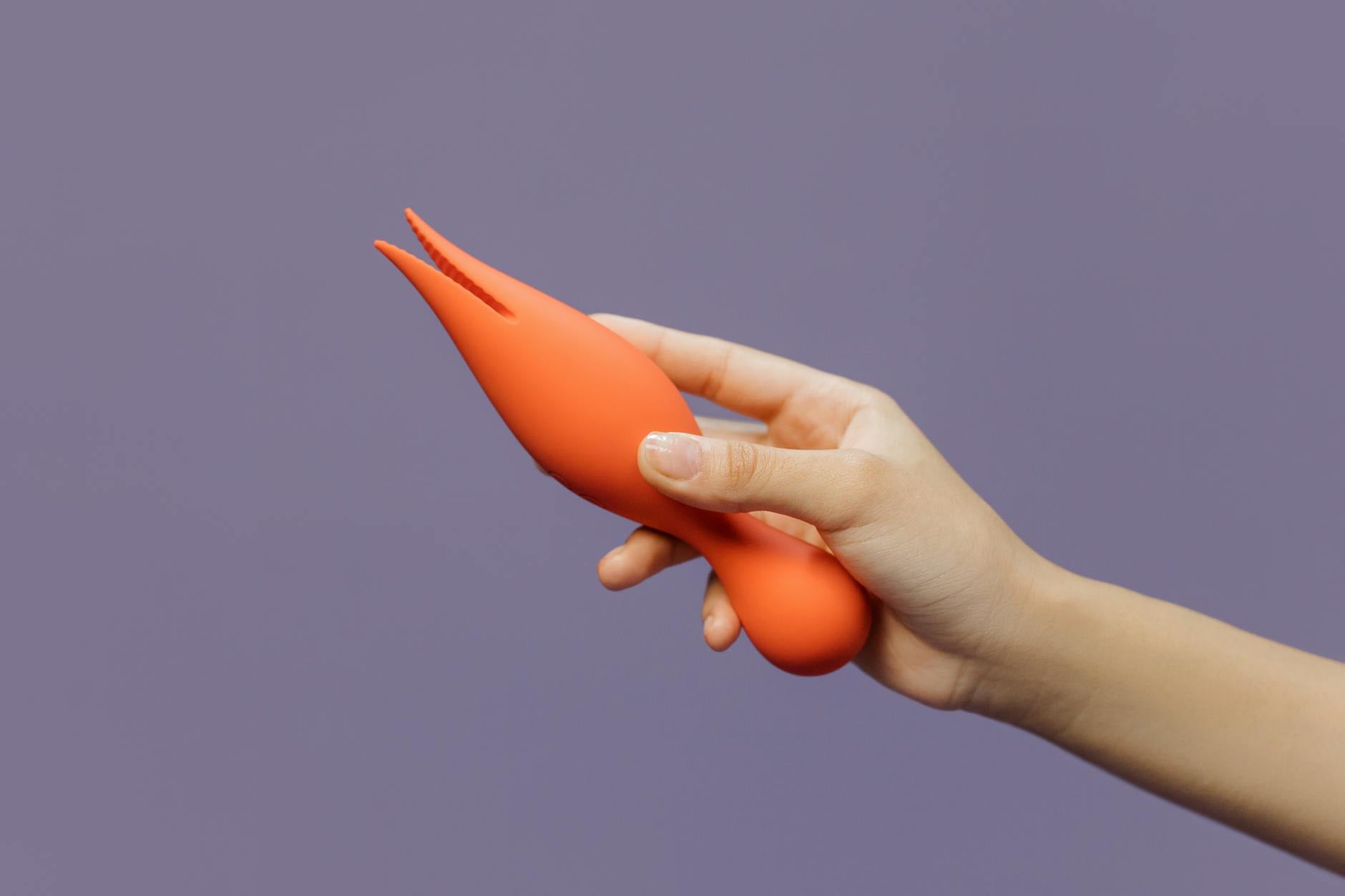 A hand holding a lemon vibrator against a purple backdrop, representing intimate self-knowledge in new relationships.
