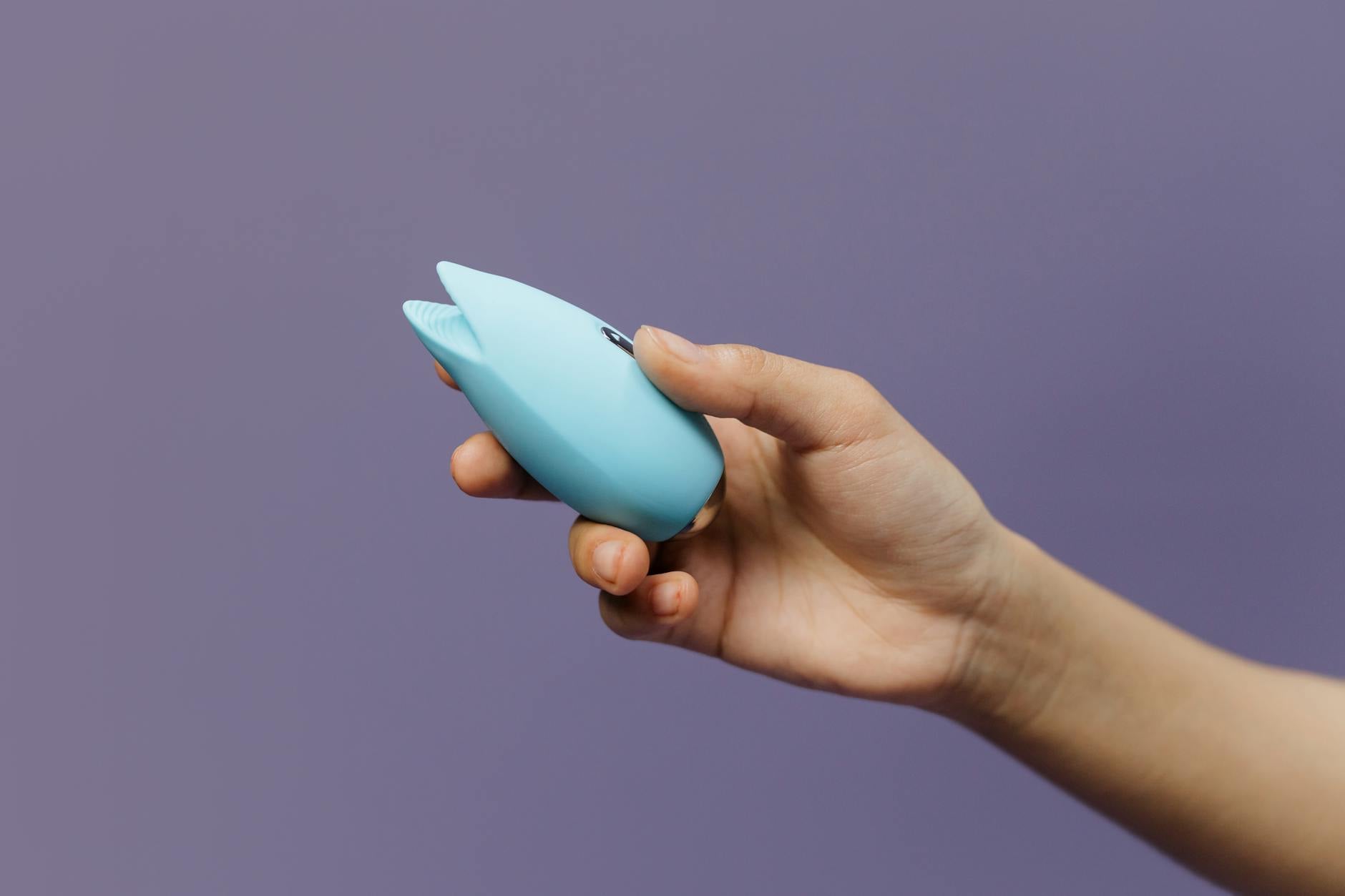Close-up of a person's hands holding a blue silicone vibrator, representing intimate self-discovery and pleasure.